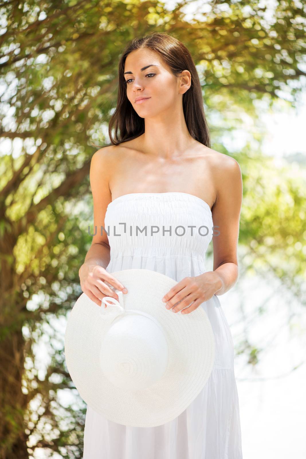 Portrait of young beautiful woman in white dress relaxing in the nature.