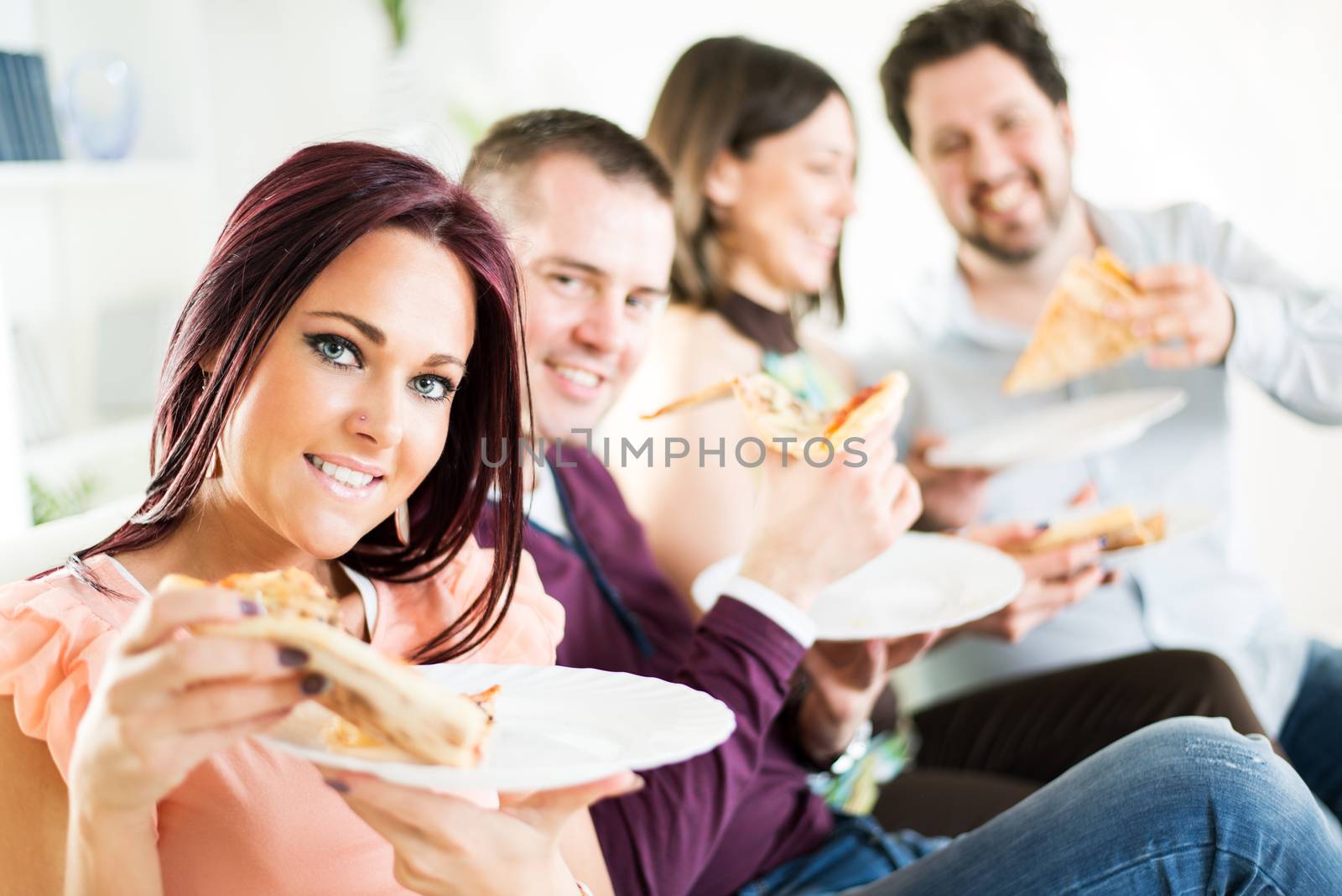Group of happy friends sitting and eating pizza at Home Interior.