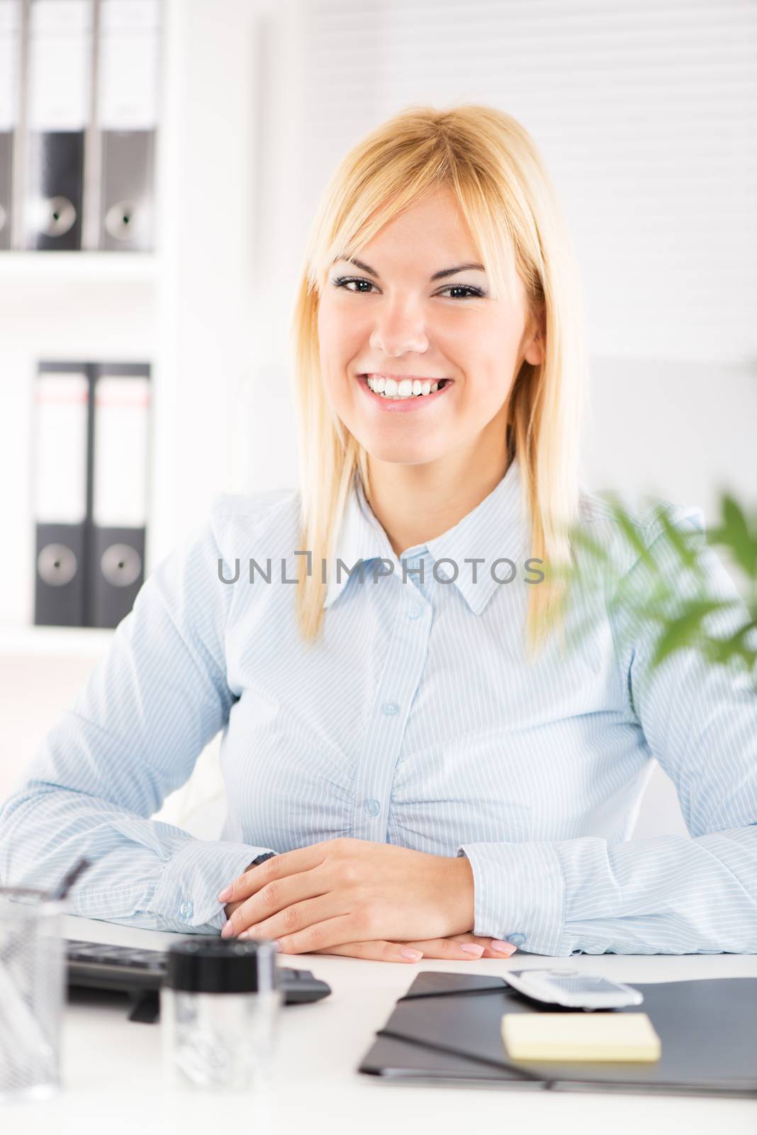 Businesswoman in the office sitting at the table and looking at camera.