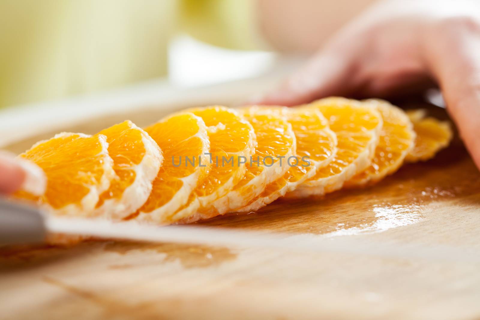 Female hands Cutting Orange in a kitchen. Close-up. Selective Focus.