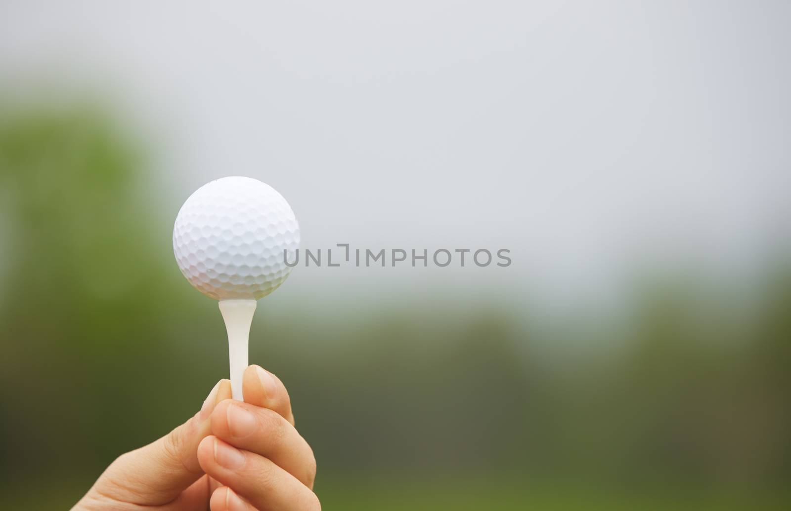 Human hand holding golf ball on a support