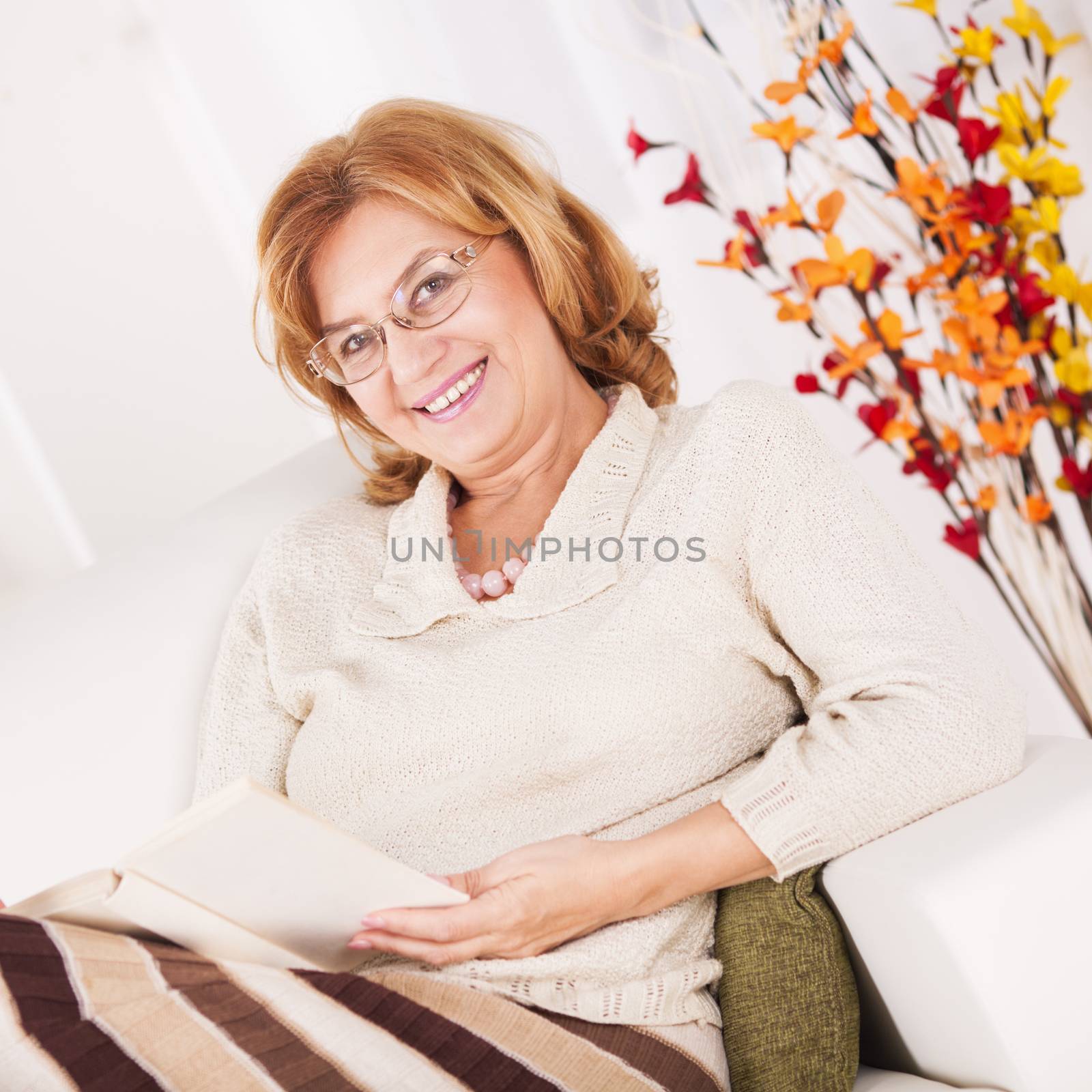 Senior woman sitting in a living room and read book.