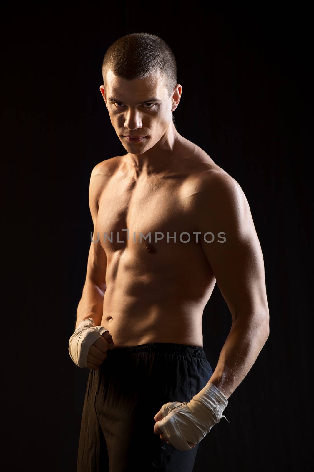 Male Fighter posing on black background.