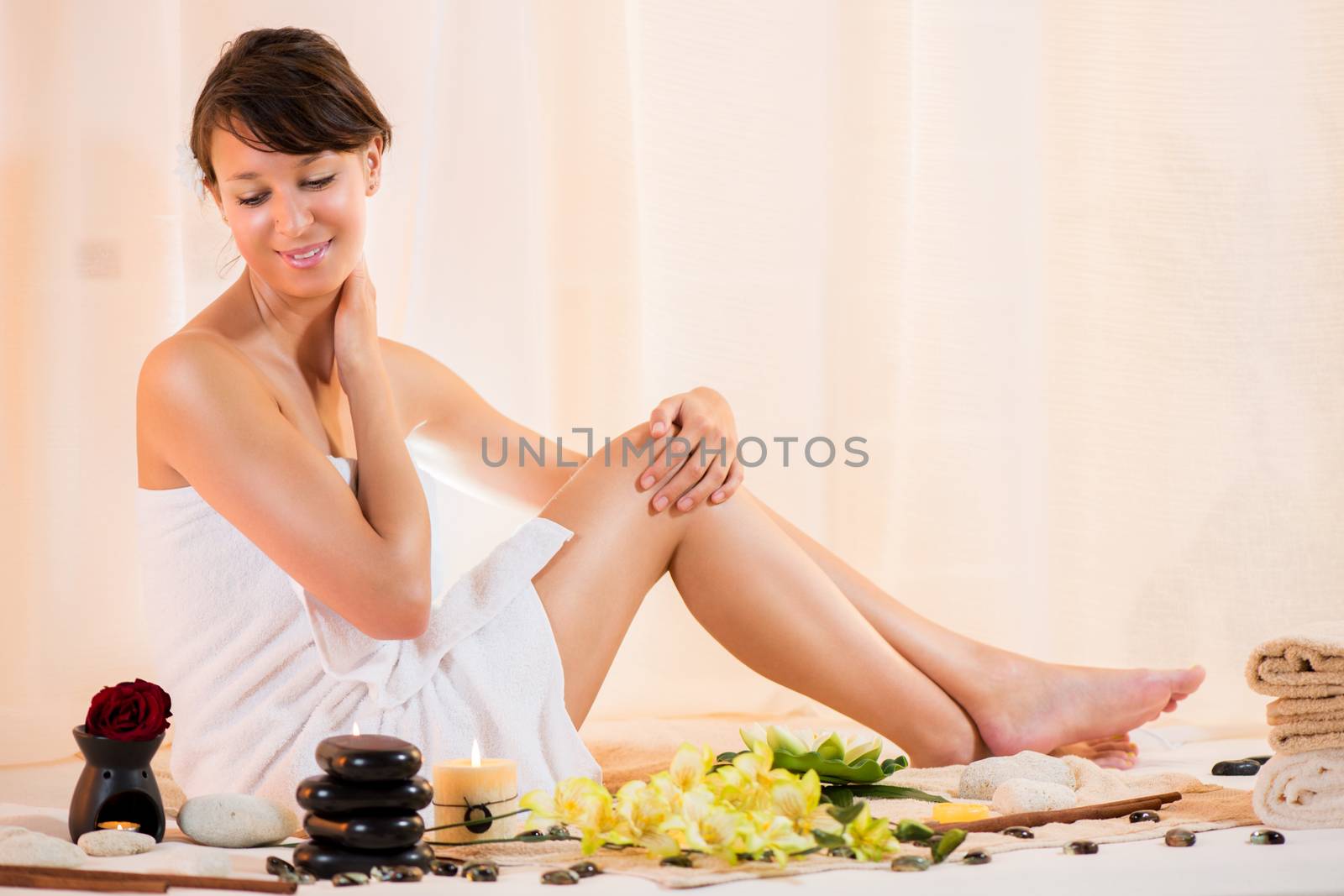 Young beautiful woman with a towel on her head body enjoying in spa salon.