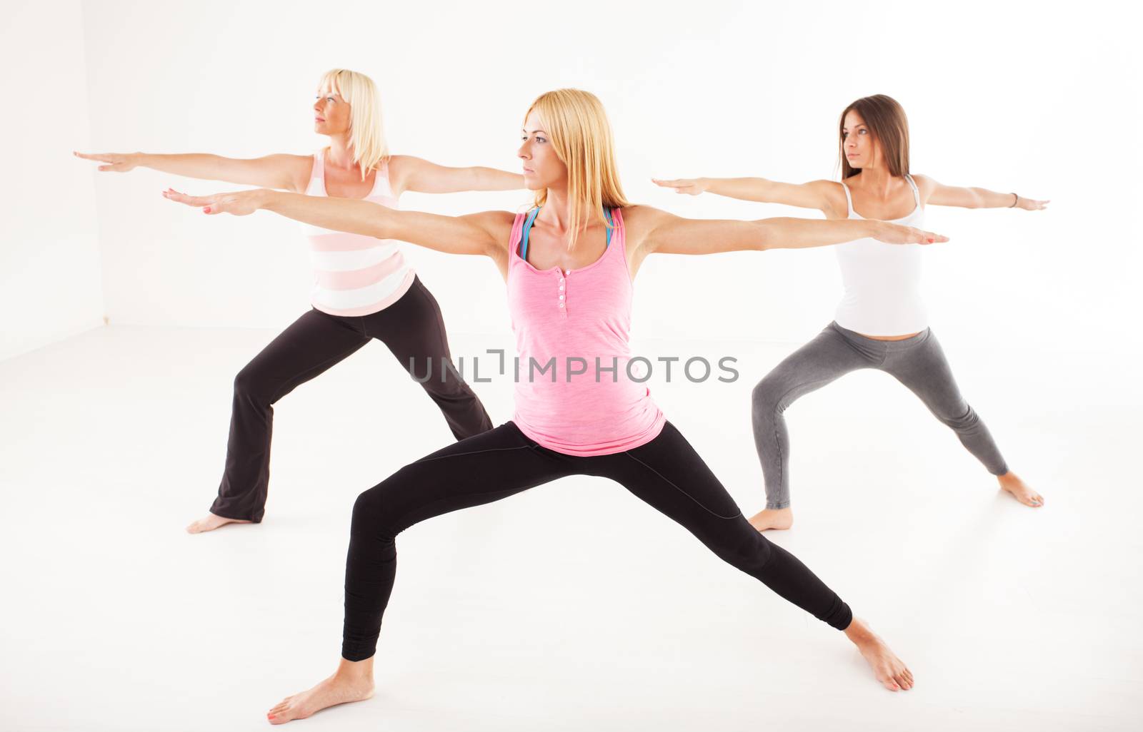 Three beautiful women doing Yoga Warrior II Pose.
