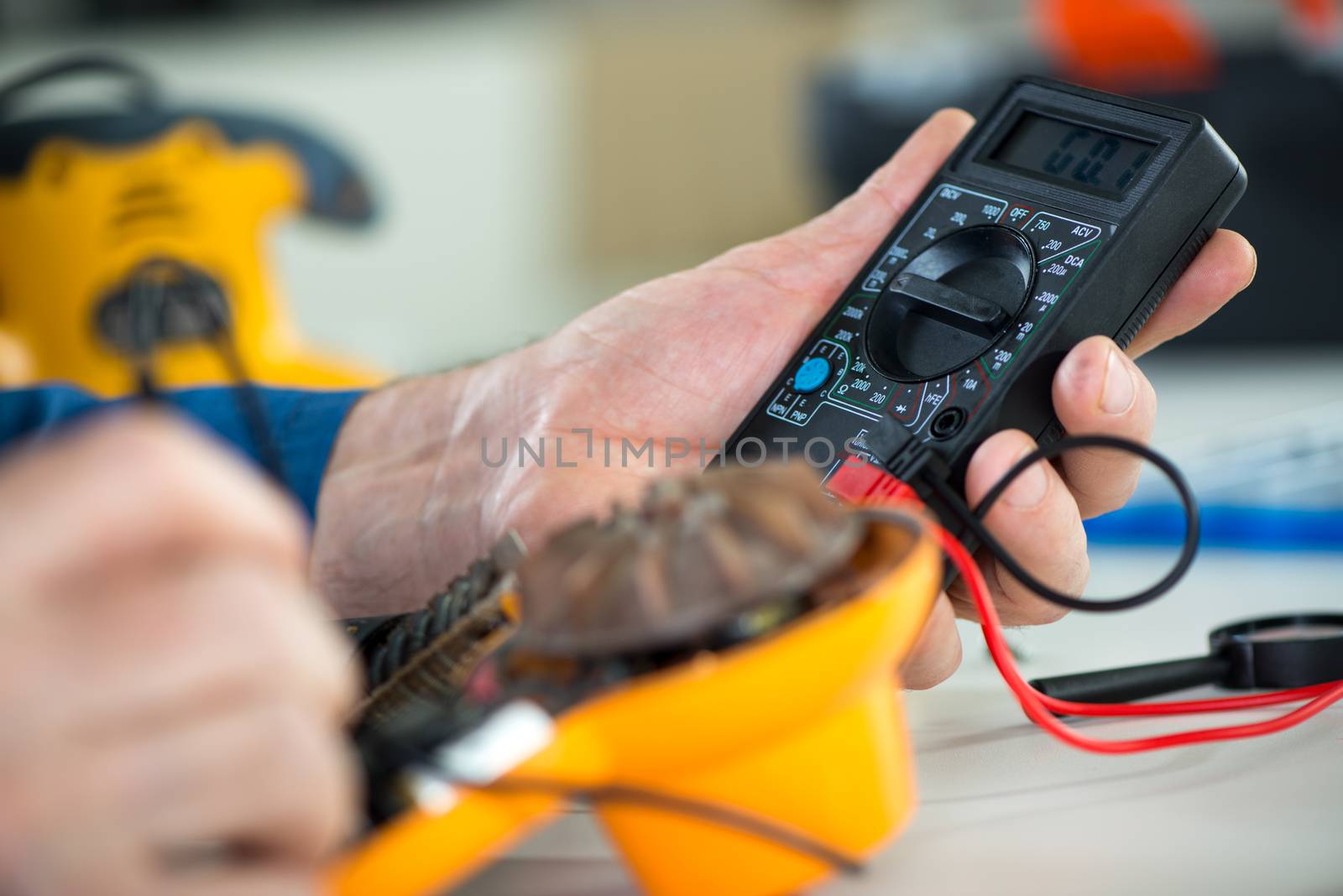 Electrician using Digital Voltmeter for Testing Voltage on old hair dryer. Close Up. Selective focus.