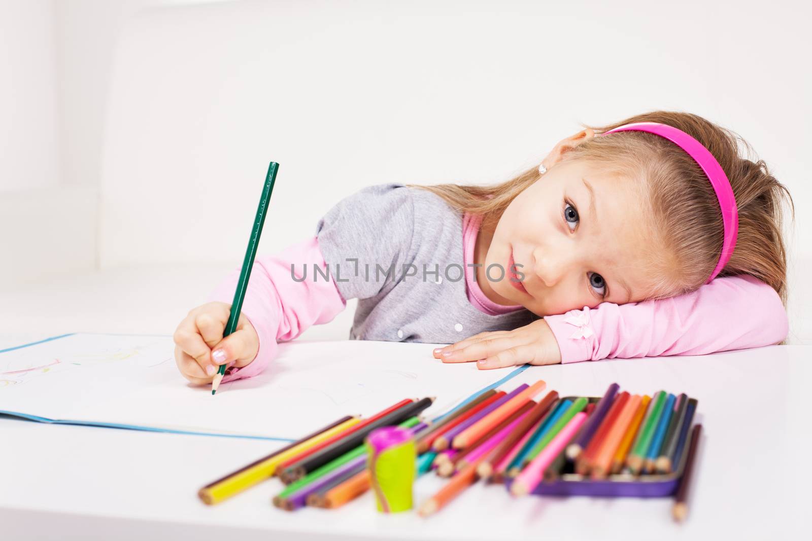 Cute little girl drawing colored pencils at home.