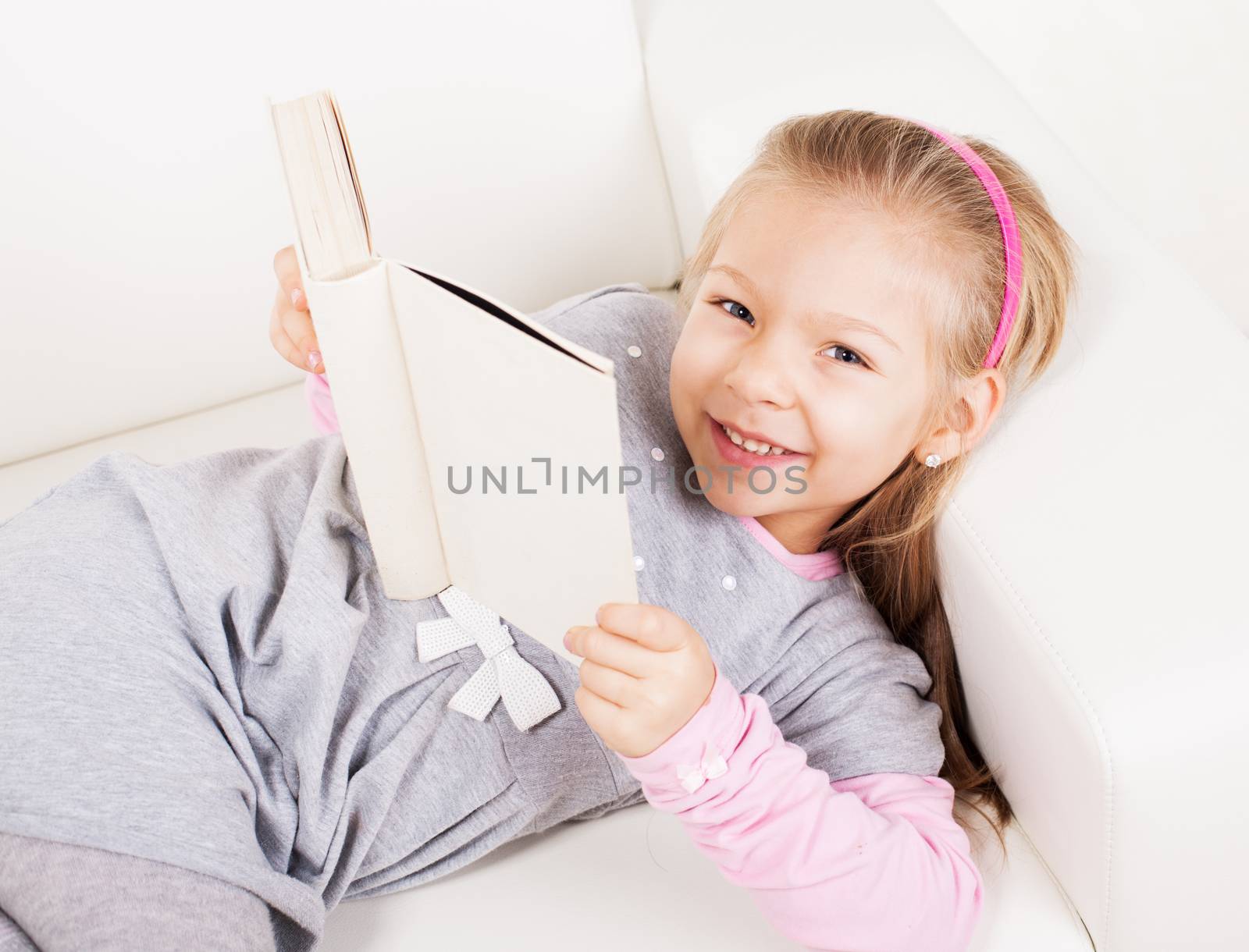 Cute little girl at home reading book.