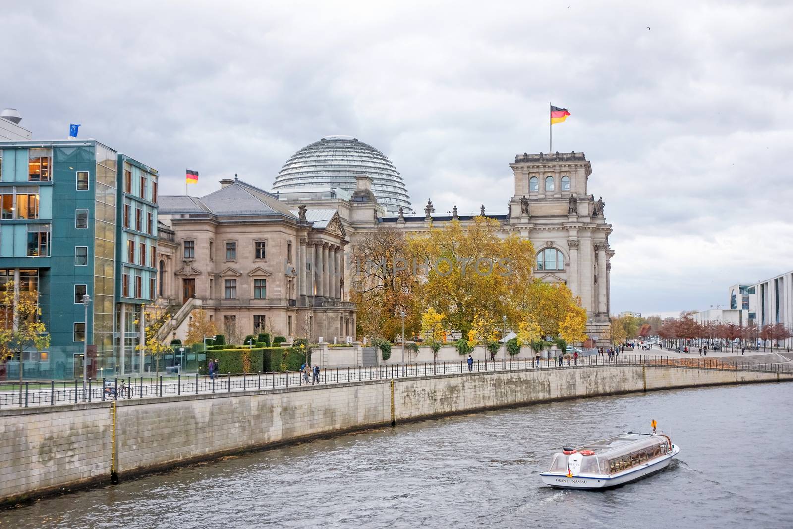 Berlin, Germany - October 28, 2013: Spree river with sightseeing passenger boat and Reichstag building in the background. Government district in Berlin-Mitte, where politic is made in Germany.