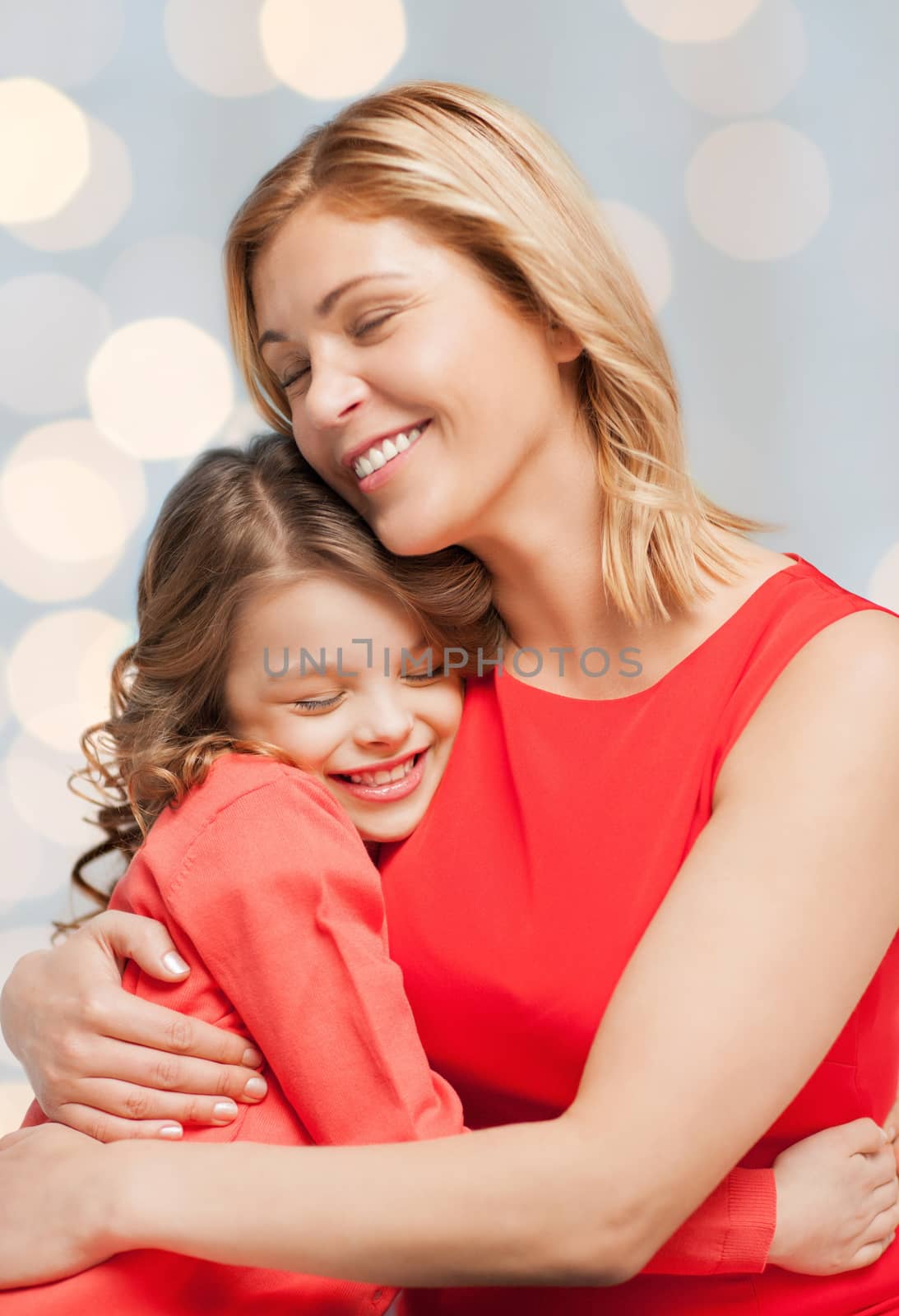 people, happiness, love, family and motherhood concept - happy mother and daughter hugging over holiday lights background