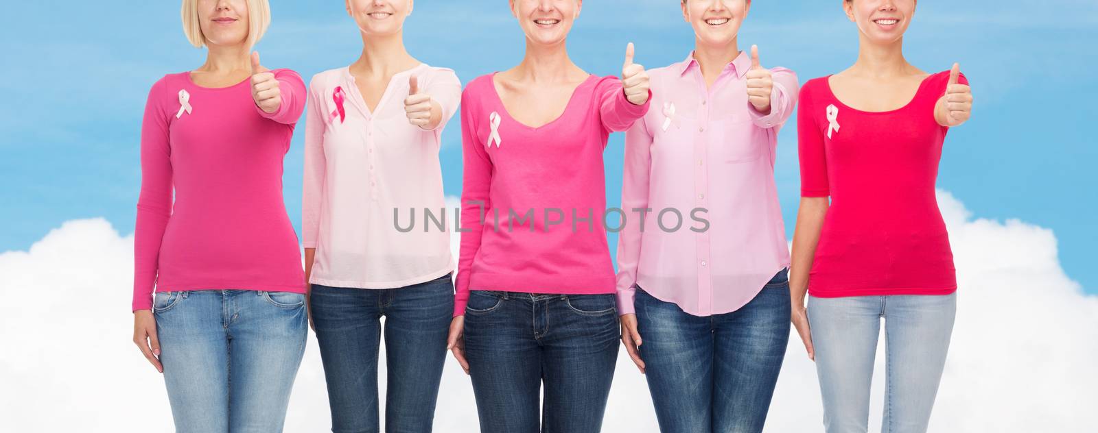 healthcare, people, gesture and medicine concept - close up of smiling women in blank shirts with pink breast cancer awareness ribbons over blue sky and white cloud background