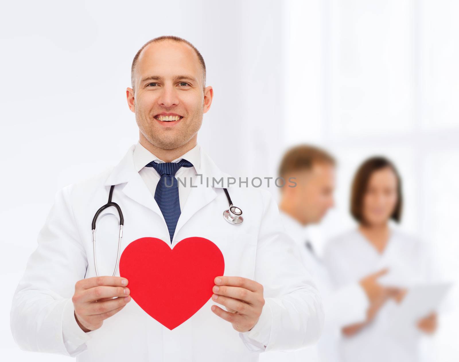 medicine, profession, charity and healthcare concept - smiling male doctor with red heart and stethoscope over group of medics