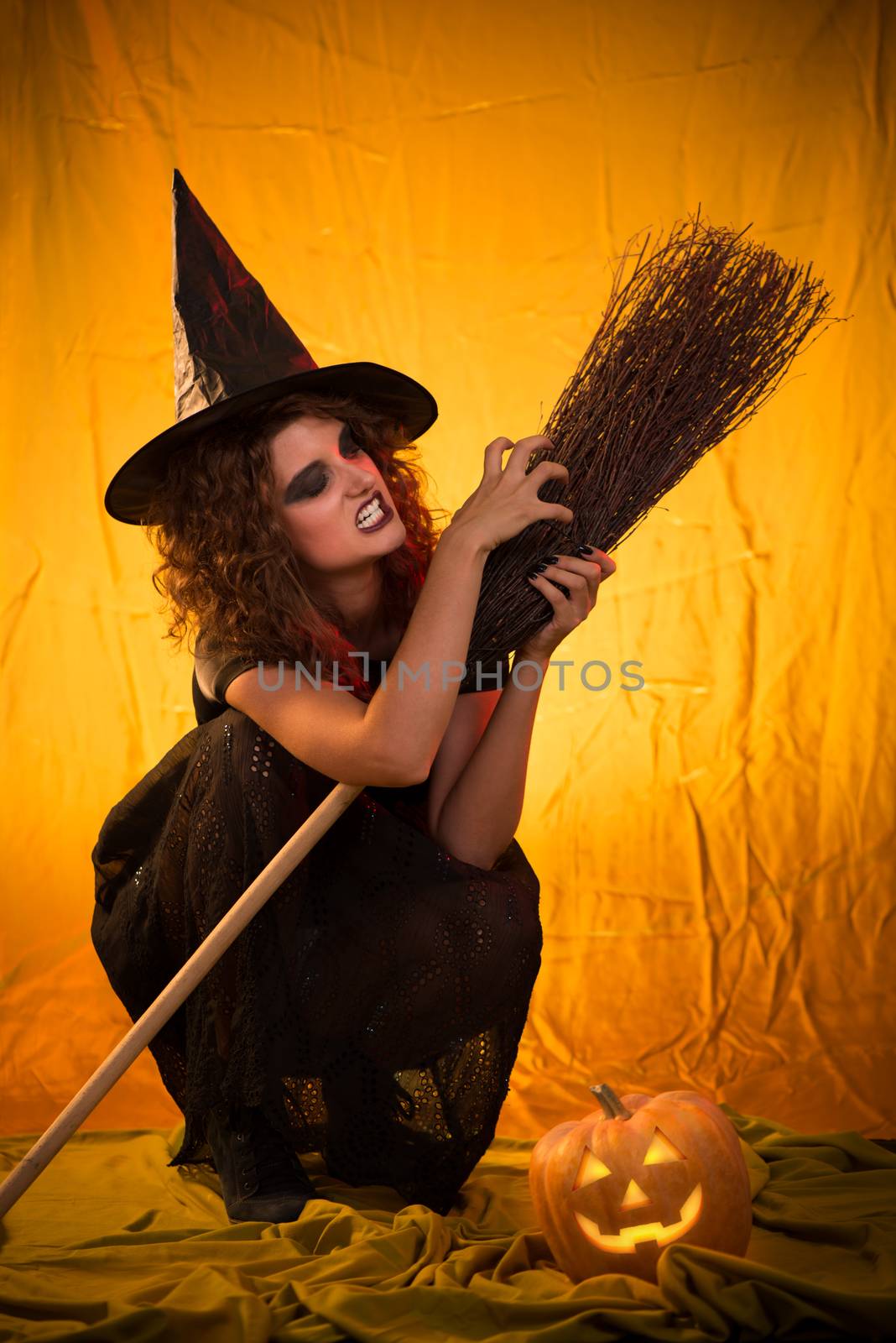 Young woman dressed like a witch. She is in dark clothing with broom.