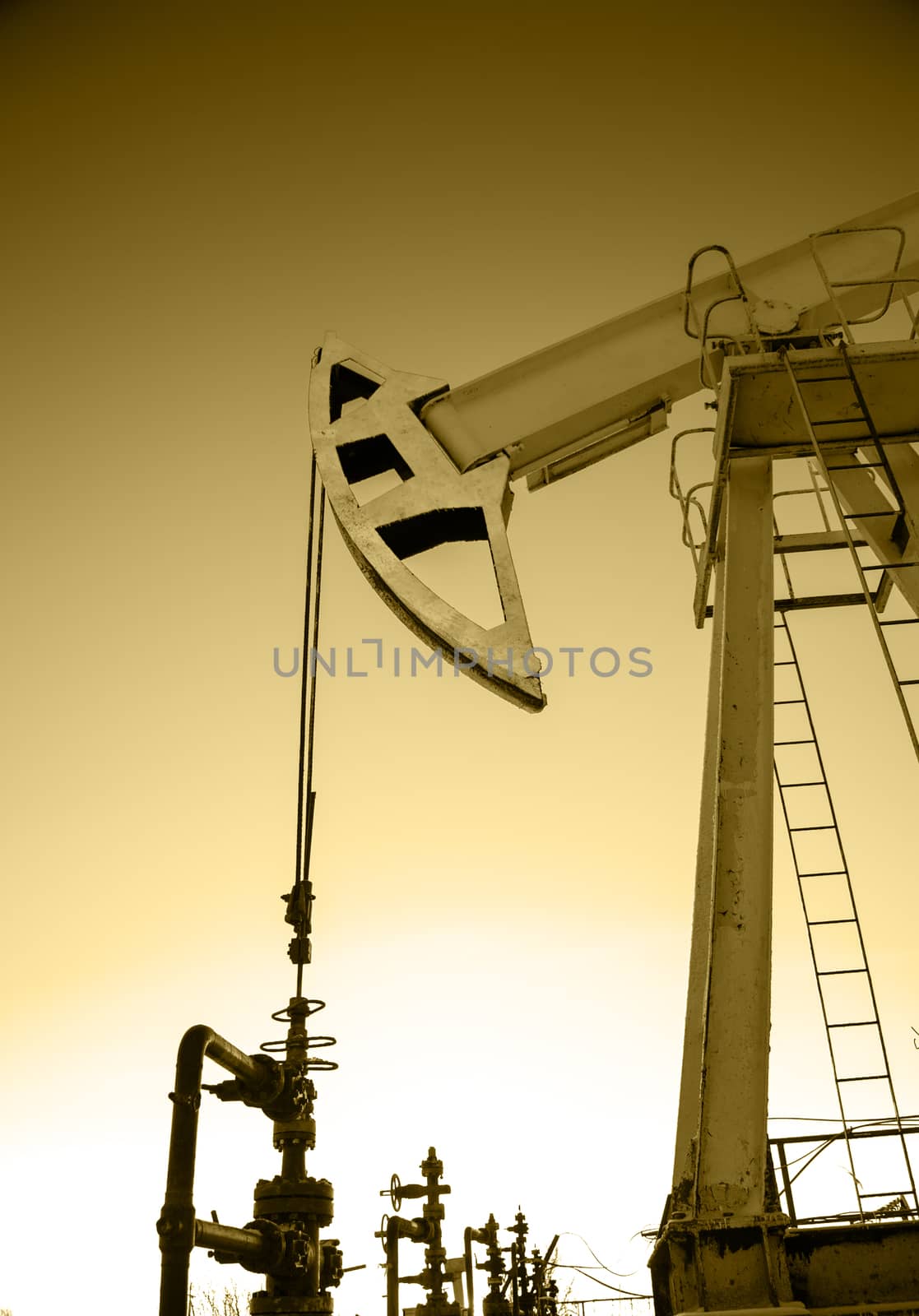 Pump jack and wellheads. Extraction of oil. Toned sepia.