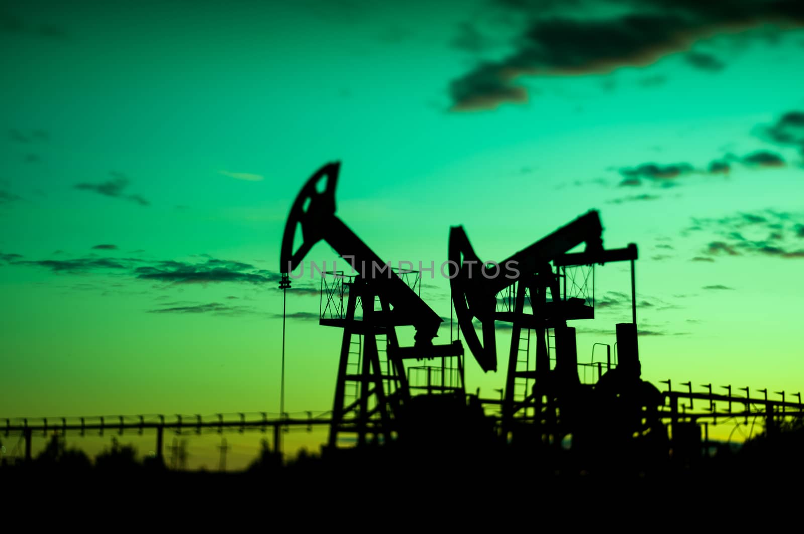 Oil pump jacks at sunset sky background. Selective focus, shallow depth of field.