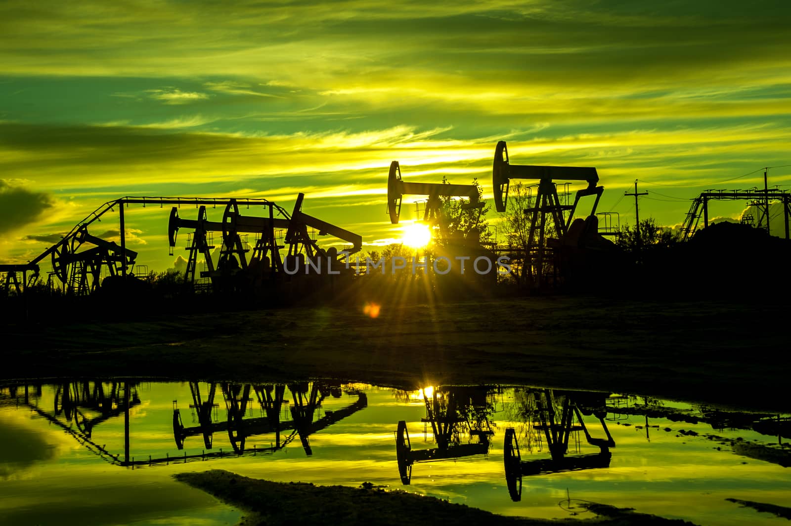 Oil pump jacks at sunset sky background. Toned.