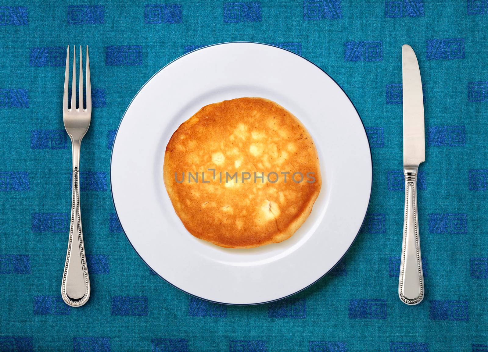 round white plate with cake, knife and fork on table