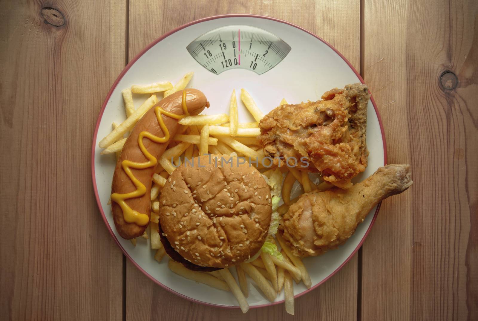 Plate packed with junk food with weighing scales 