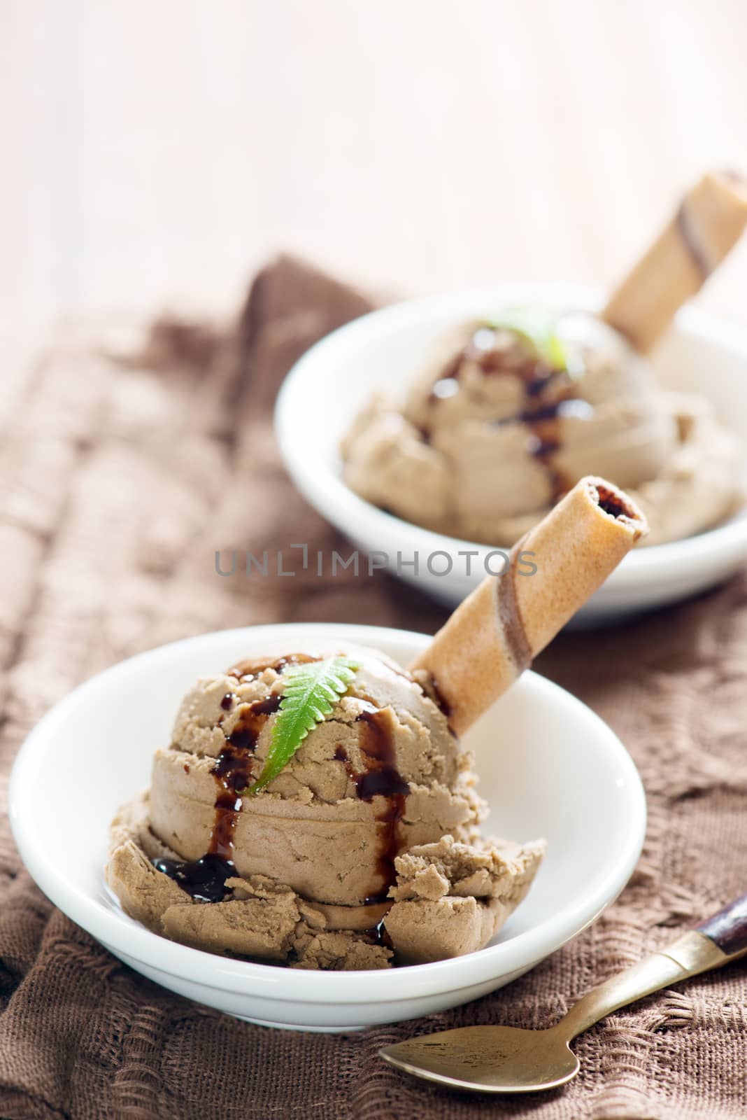 Chocolate ice cream with wafer on plate, table cloth background.