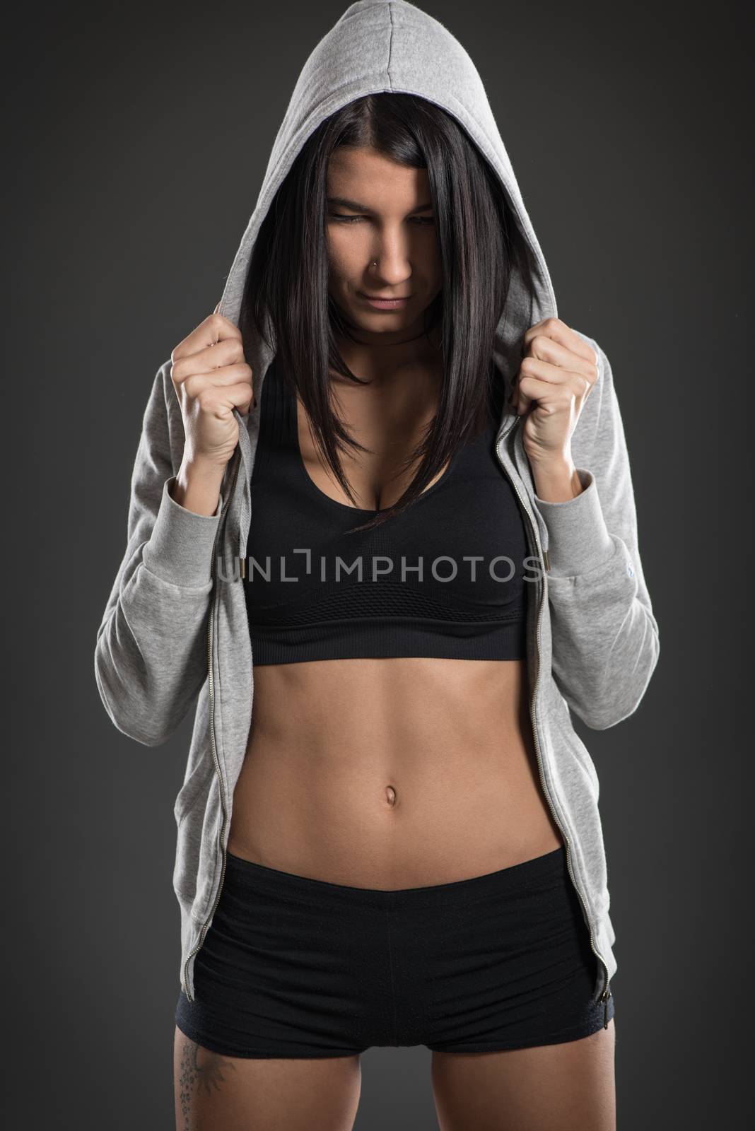 Attractive muscular young woman posing in studio on dark background 
