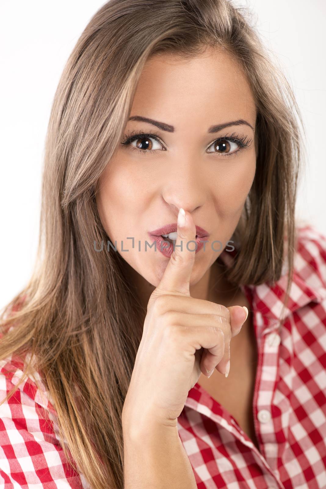 Portrait of beautiful young woman with finger on her lips gesturing for silent. Close-up. Looking at camera.