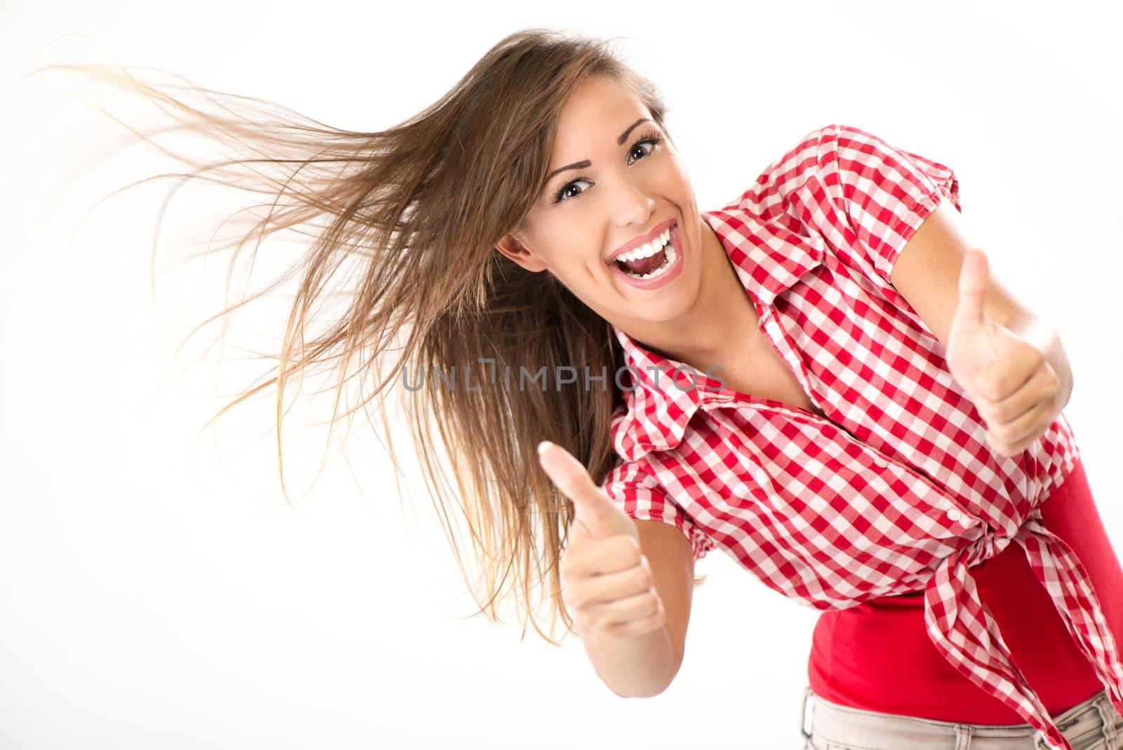 Cheerful successful young woman holding thumbs up and looking at camera.