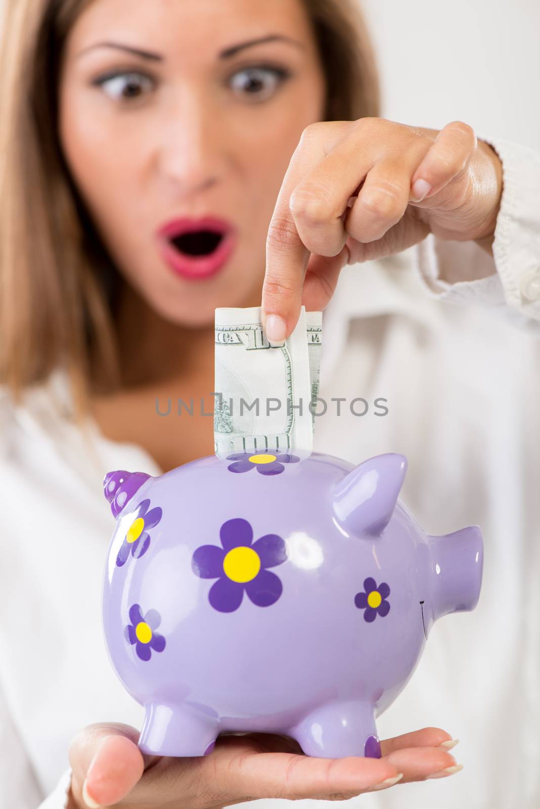 Close-up of a businesswoman hand putting money in piggy bank. Saving and financial concept. Selective focus. Focus on piggy bank, on foreground.