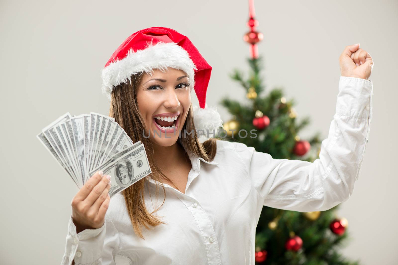 Successful businesswoman wearing santa hat and holding money. 