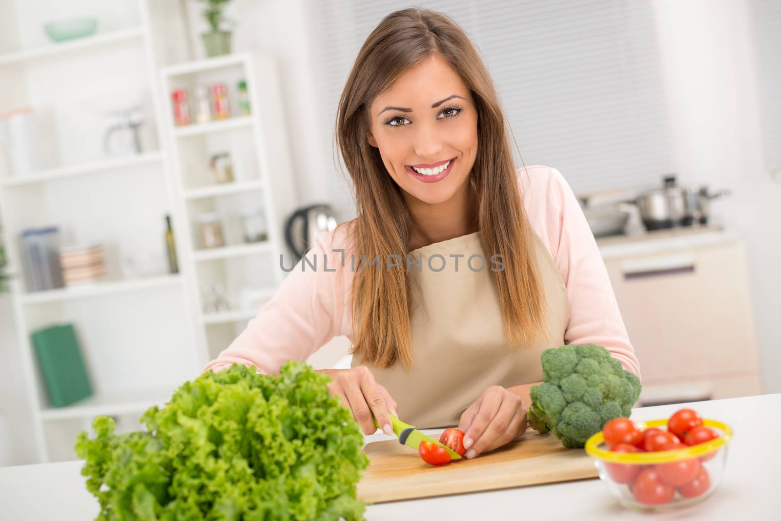 Beautiful young woman in the kitchen preparing vegetarian food.