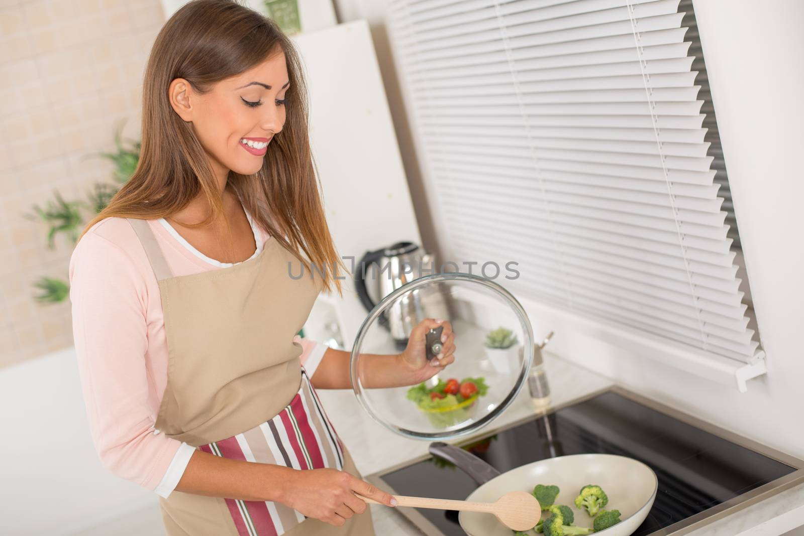 Young beautiful woman cooking healthy meal in the kitchen.