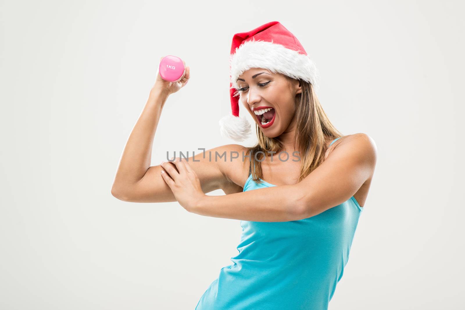 Beautiful fitness woman wearing santa hat doing exercise training arms lifting dumbbells.