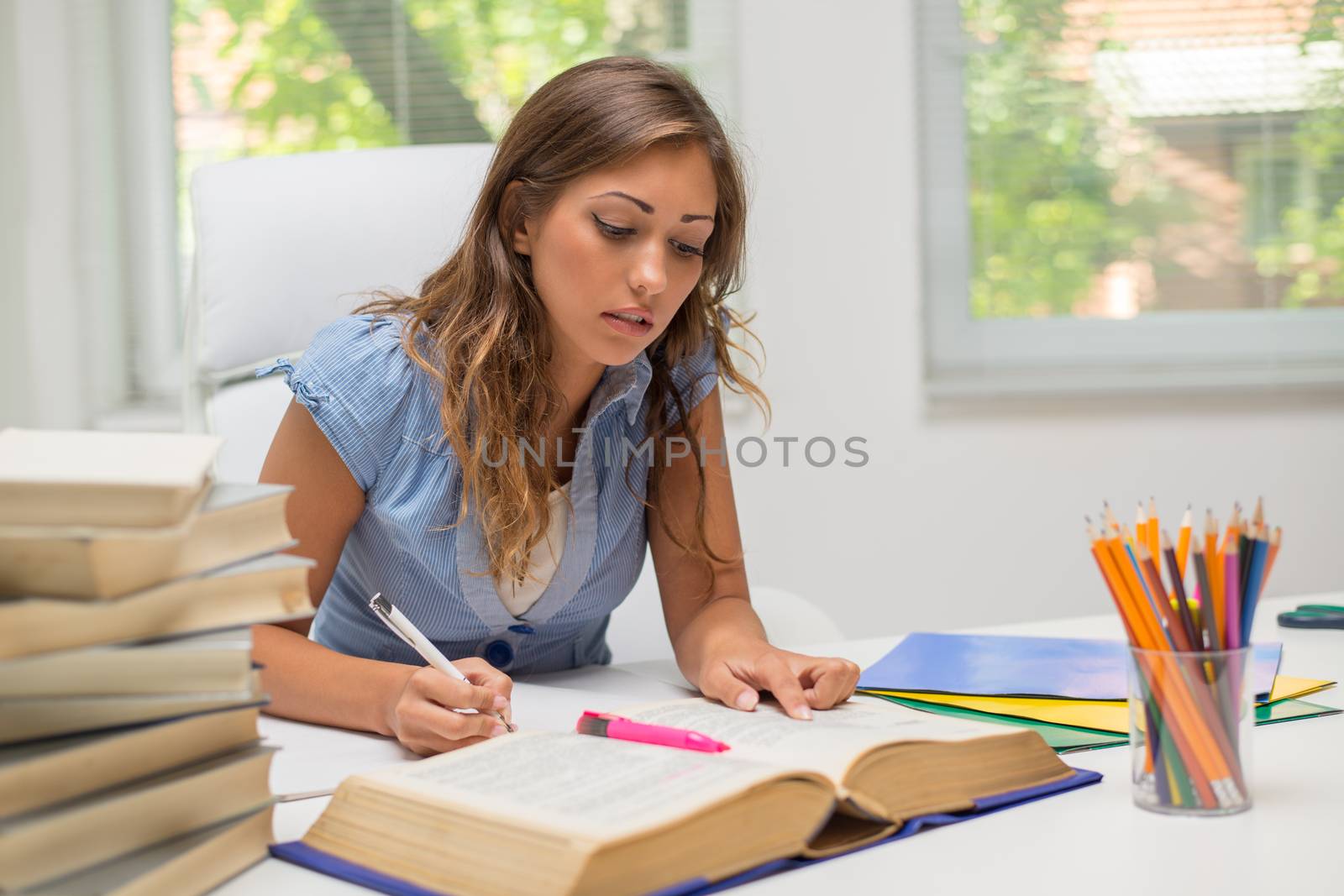 Beautiful teenage girl with many textbooks learning in the library.