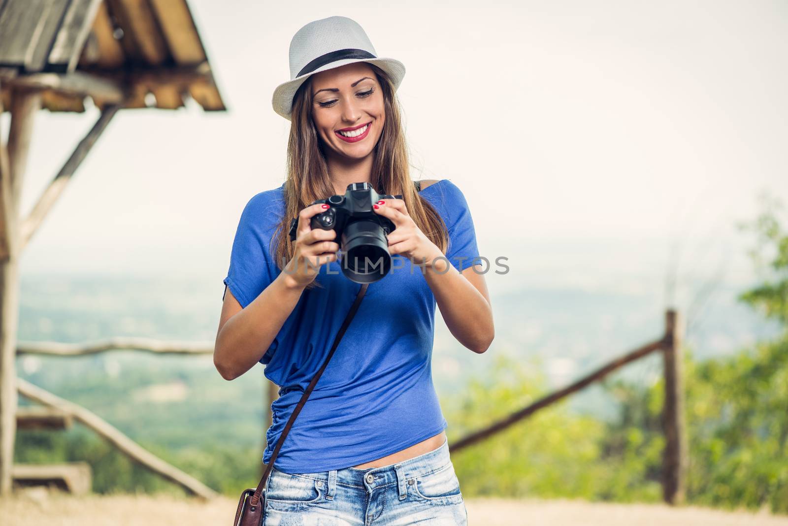 Young beautiful woman standing by viewpoint and looking photography on the digital camera.