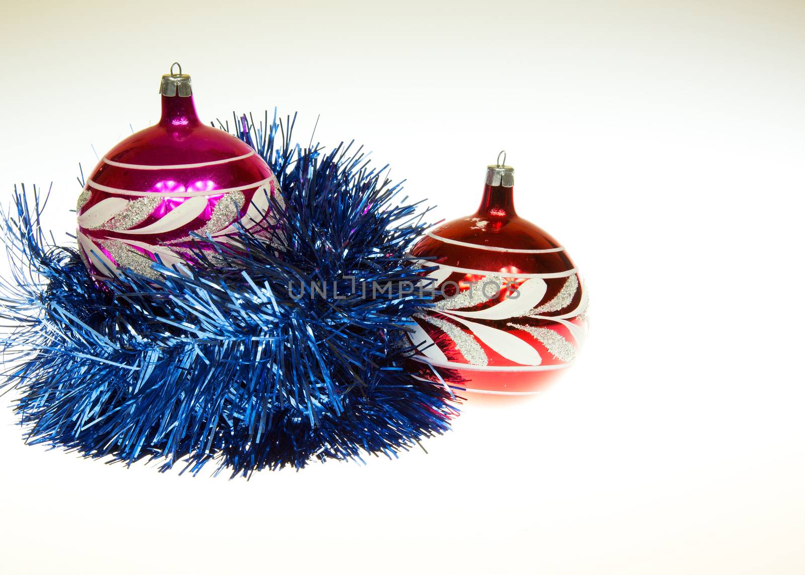 Two red Christmas balubles, one wrapped in a decorative blue chain and one on her right side. The whole on an isolated white background