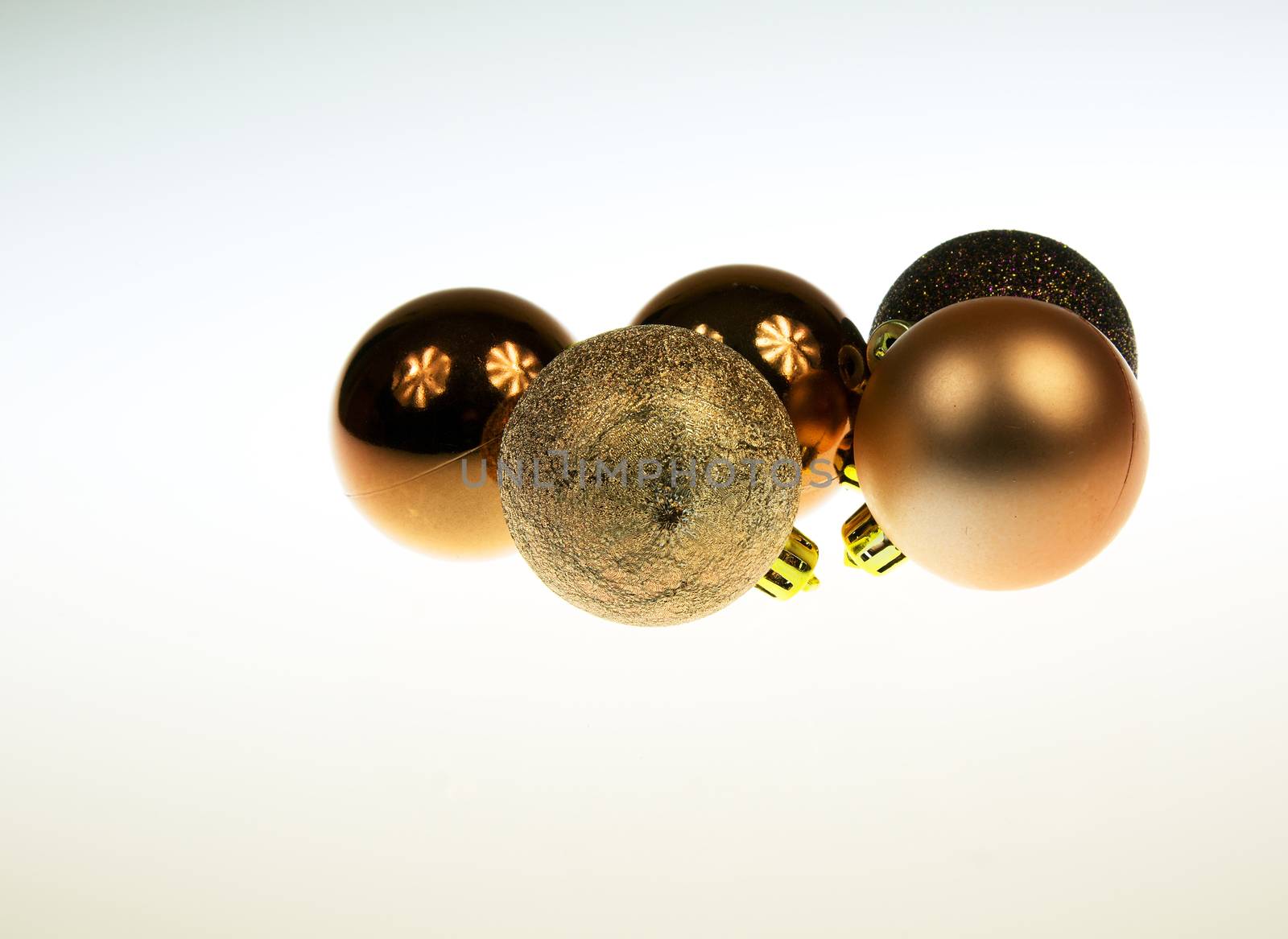 Five golden and brown Christmas baubles together  with reflections on white isolated background.Horizontal view.