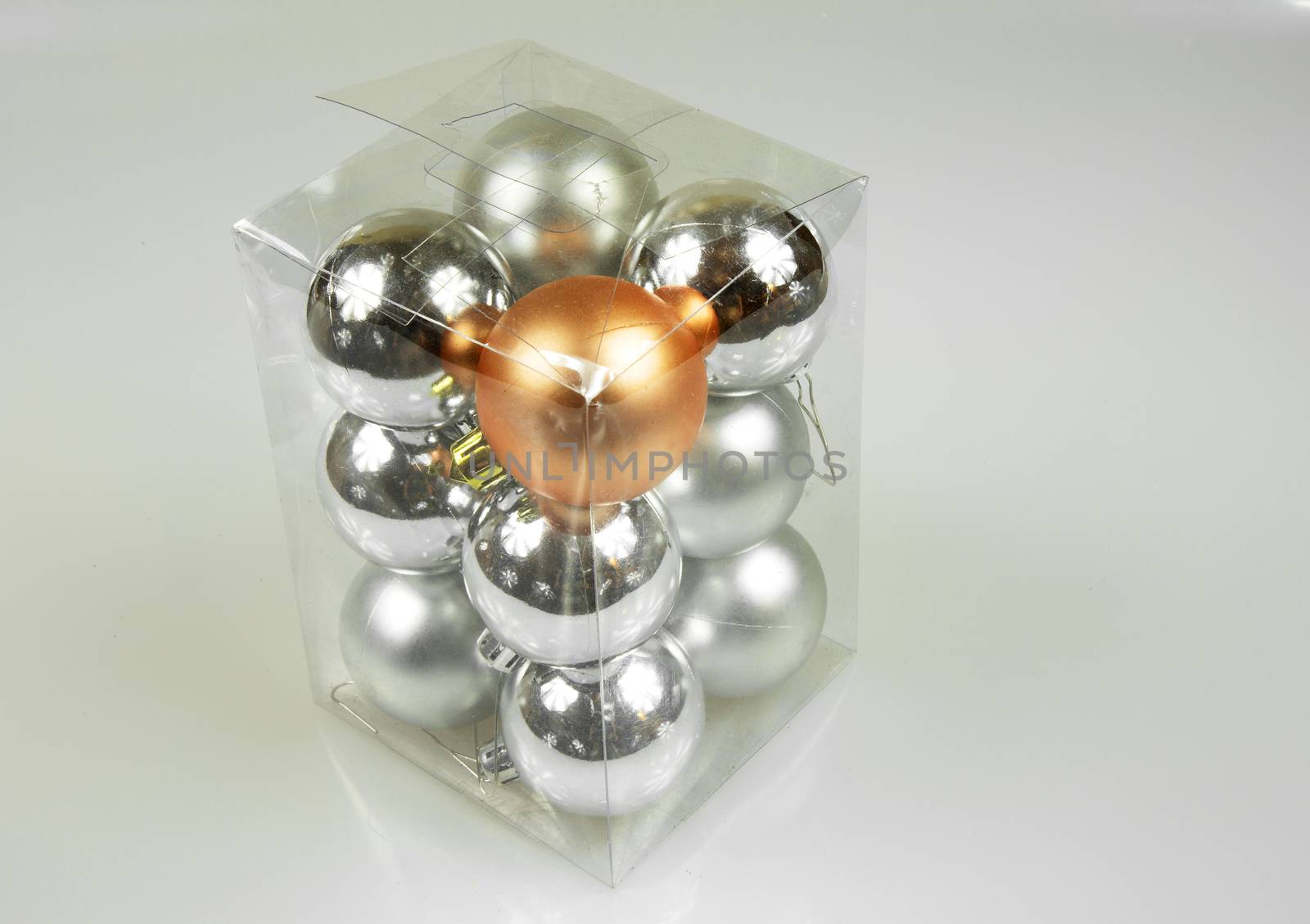 Transparent box with small Christmas trees baubles on a white background. Close view from above.