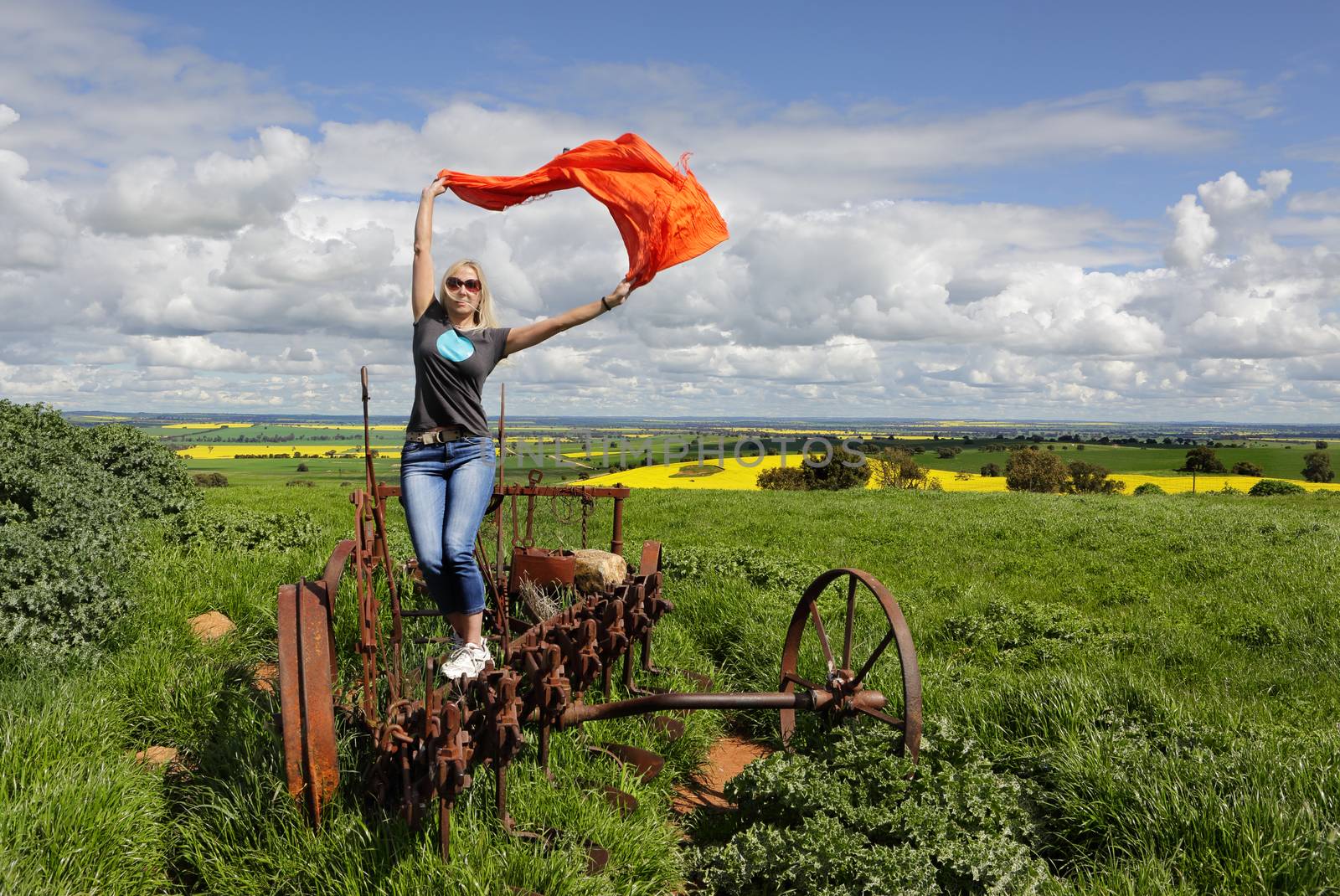 A woman on an old rusted tractor plough enjoying country life.  Wellness, fun