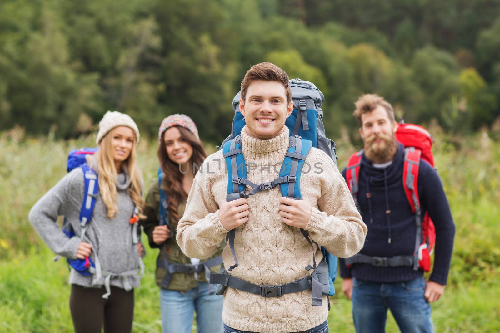 group of smiling friends with backpacks hiking by dolgachov