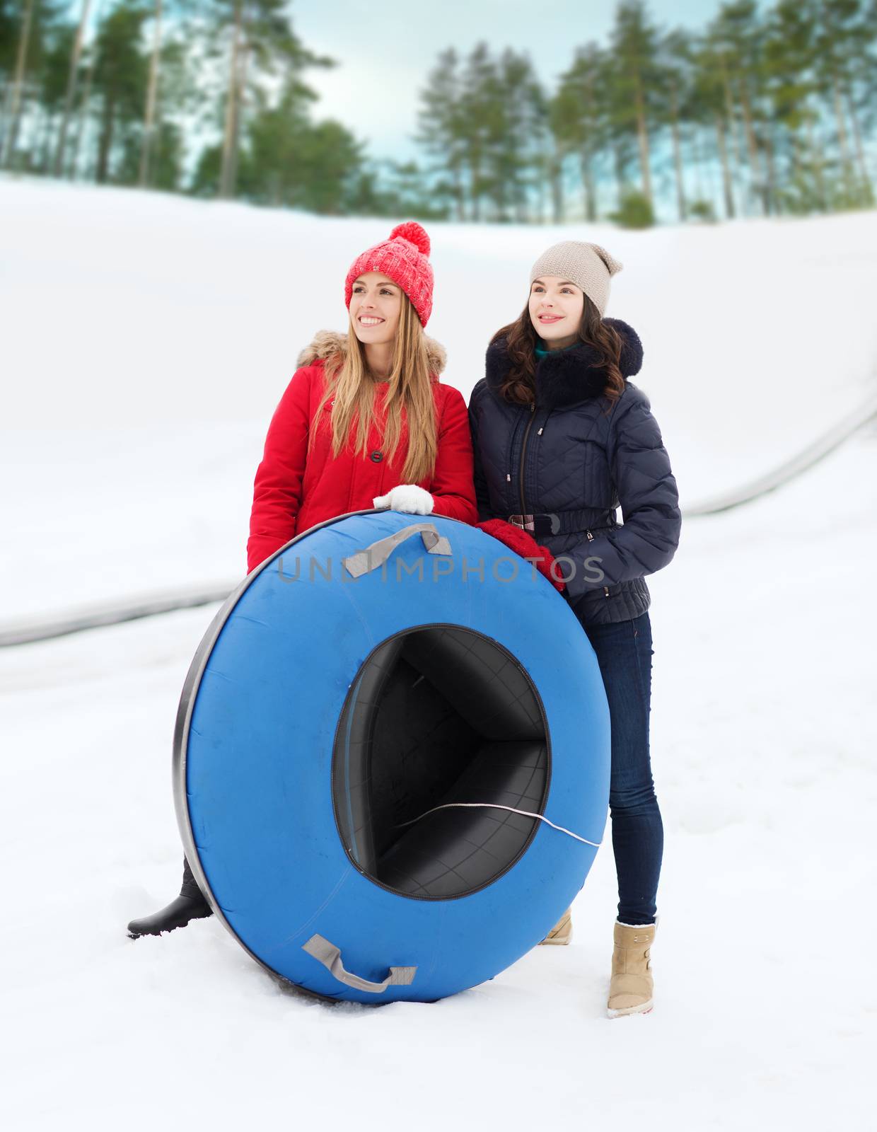 winter, leisure, sport, friendship and people concept - happy girl friends with snow tubes outdoors