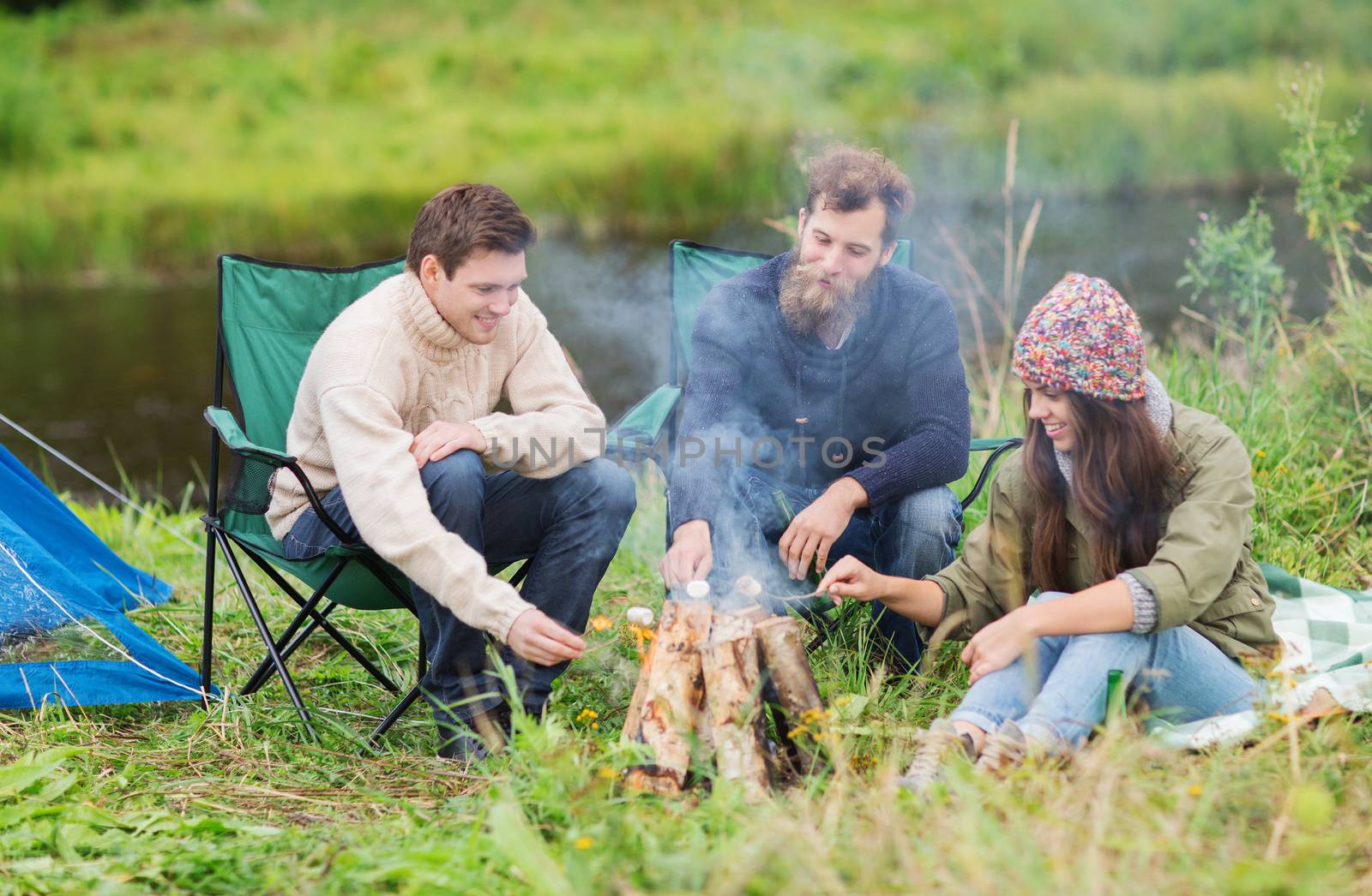 smiling tourists cooking marshmallow in camping by dolgachov