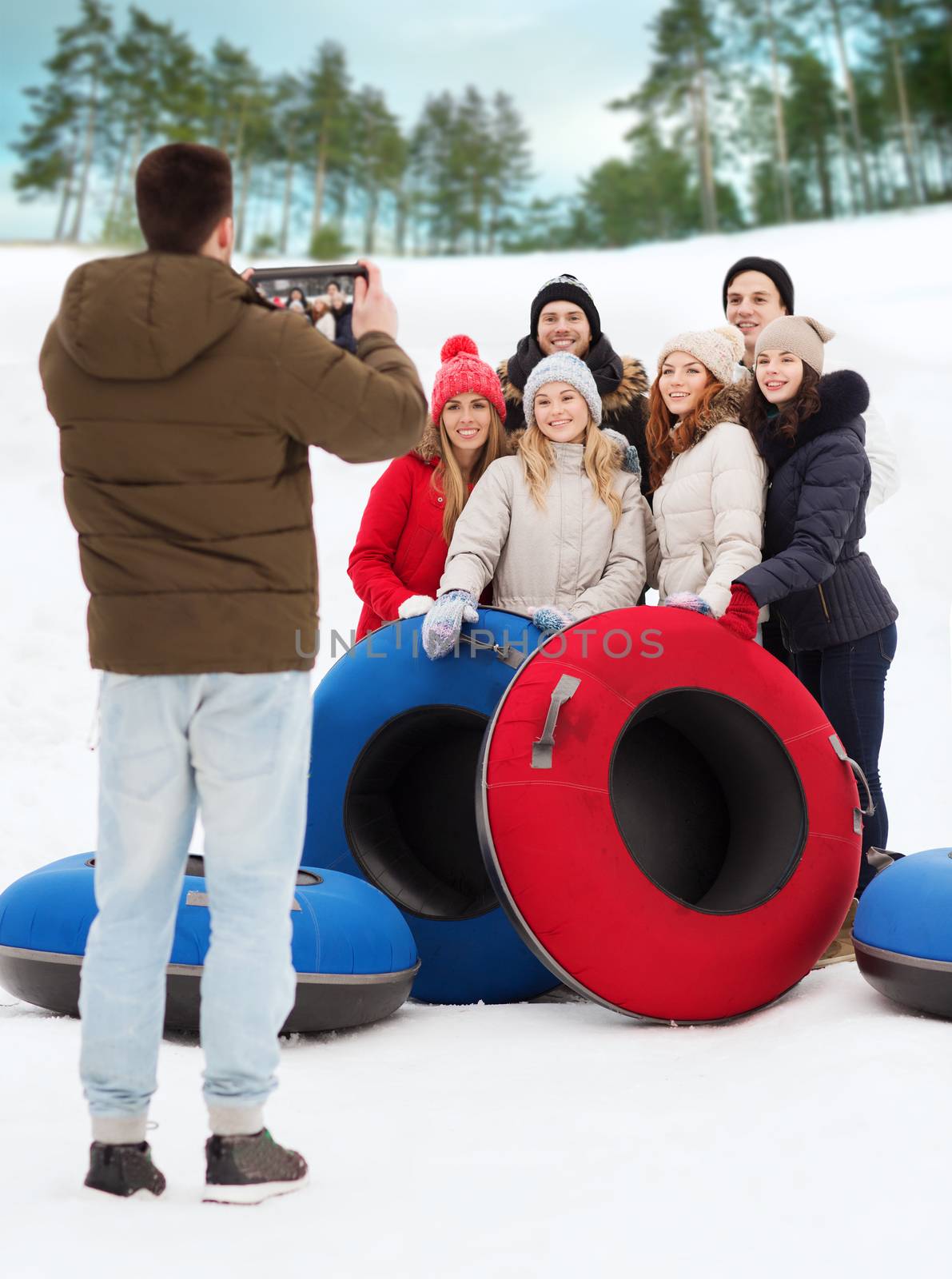 group of smiling friends with snow tubes by dolgachov