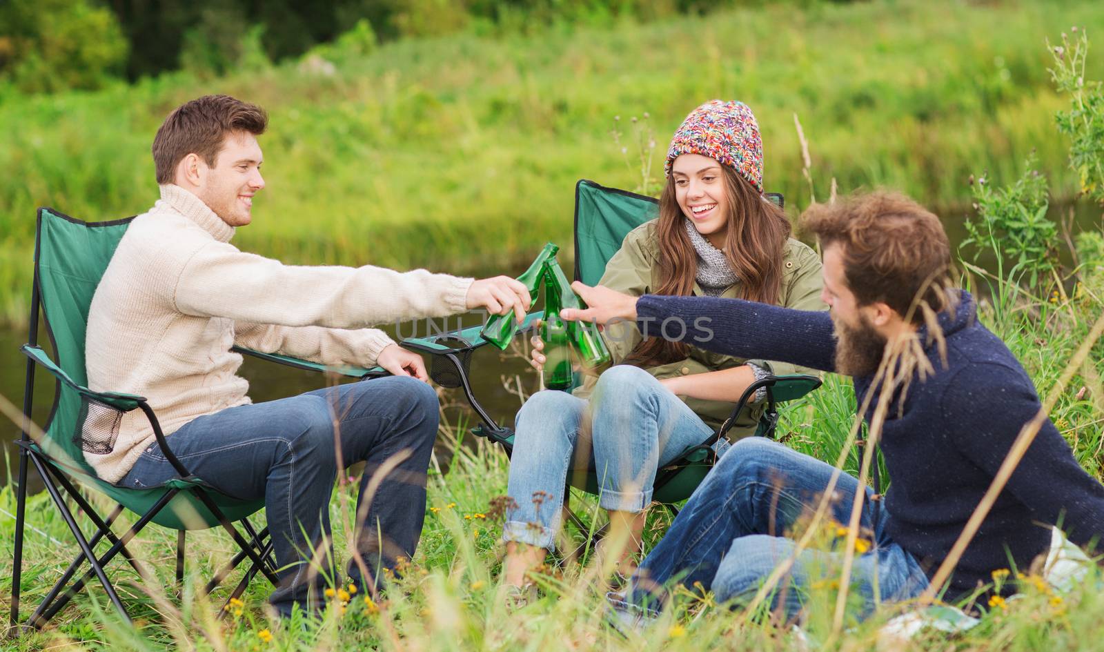 group of smiling tourists drinking beer in camping by dolgachov