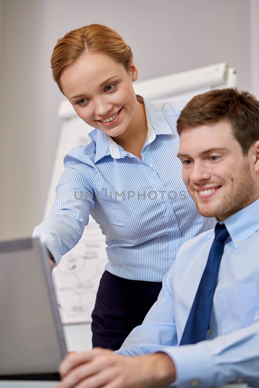 smiling businesspeople with laptop in office by dolgachov