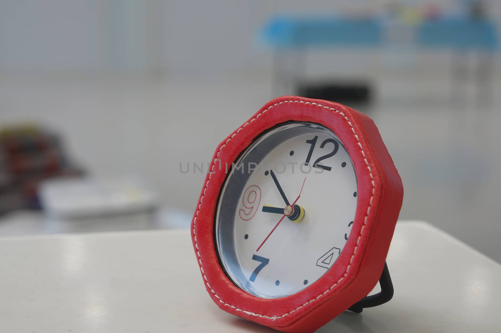 Red alarmclock for coundown placed on white table at office.                              