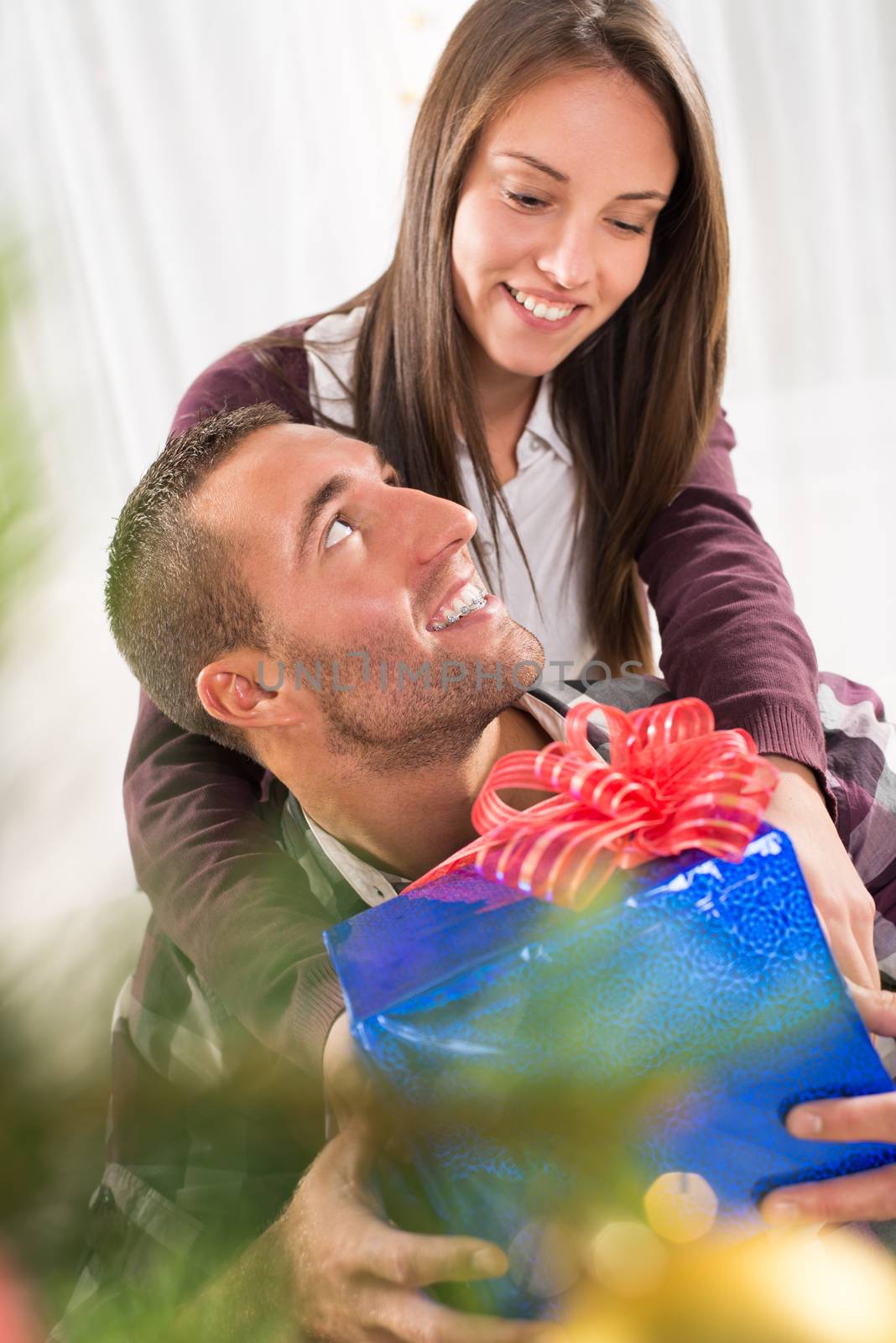 Young beautiful couple exchanging a Christmas gift.