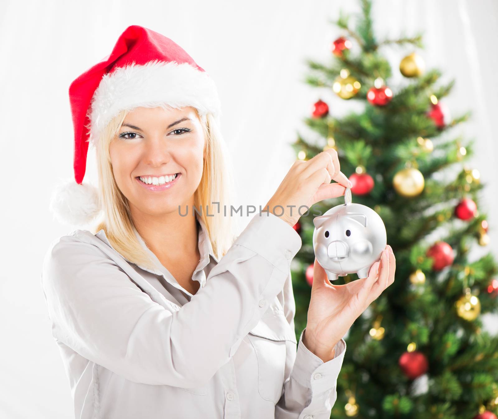 Young beautiful woman with Santa Hat holding Piggy Bank and saving money.