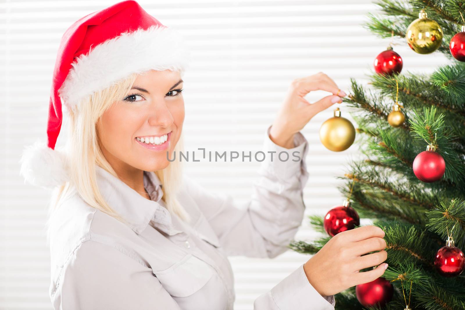 Young beautiful woman decorating Christmas tree.