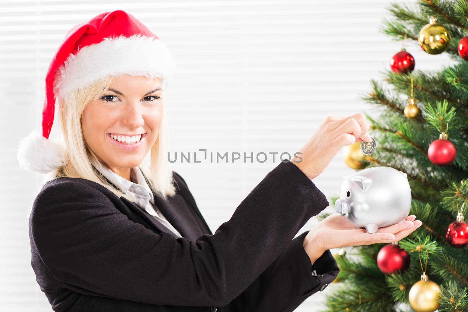 Young beautiful businesswoman with Santa Hat holding Piggy Bank and saving money.