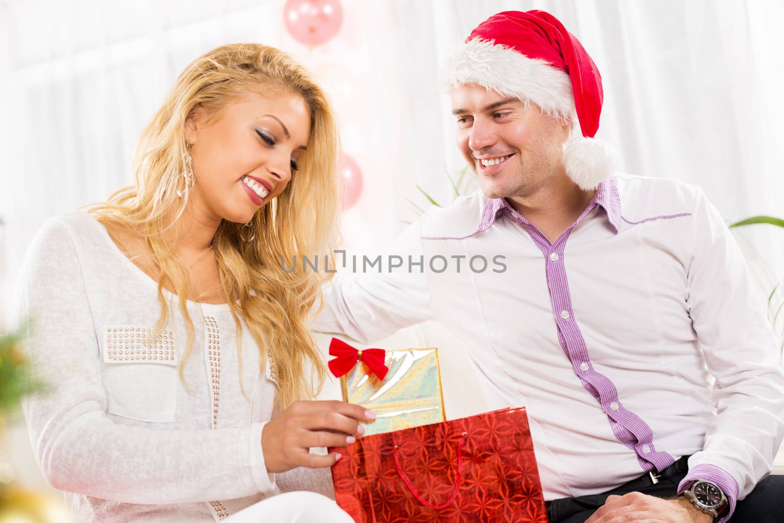 Happy young man gives his cute girlfriend a Christmas gift.