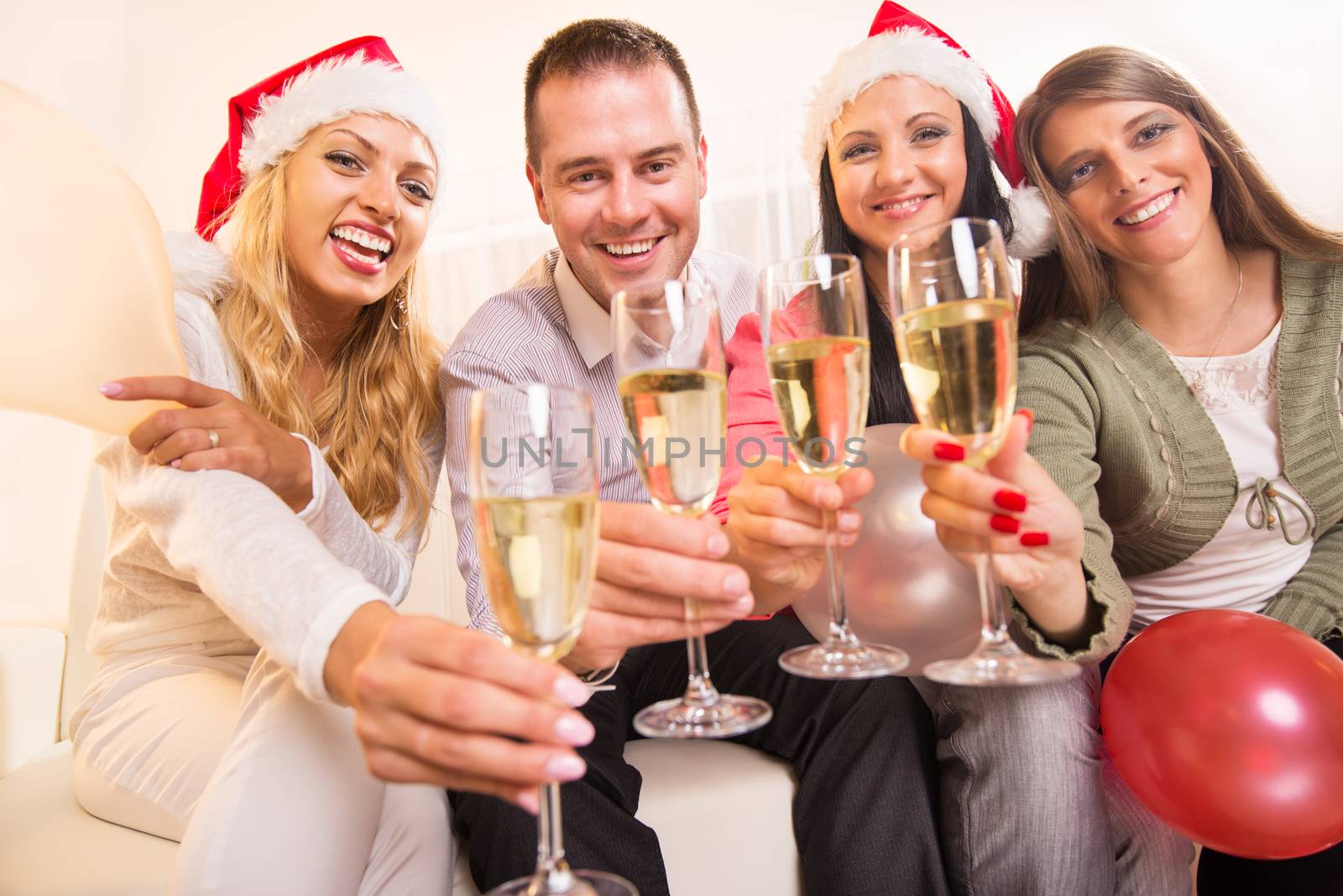 Happy friends Celebrating Christmas or New Year with glass of champagne in home interior.
